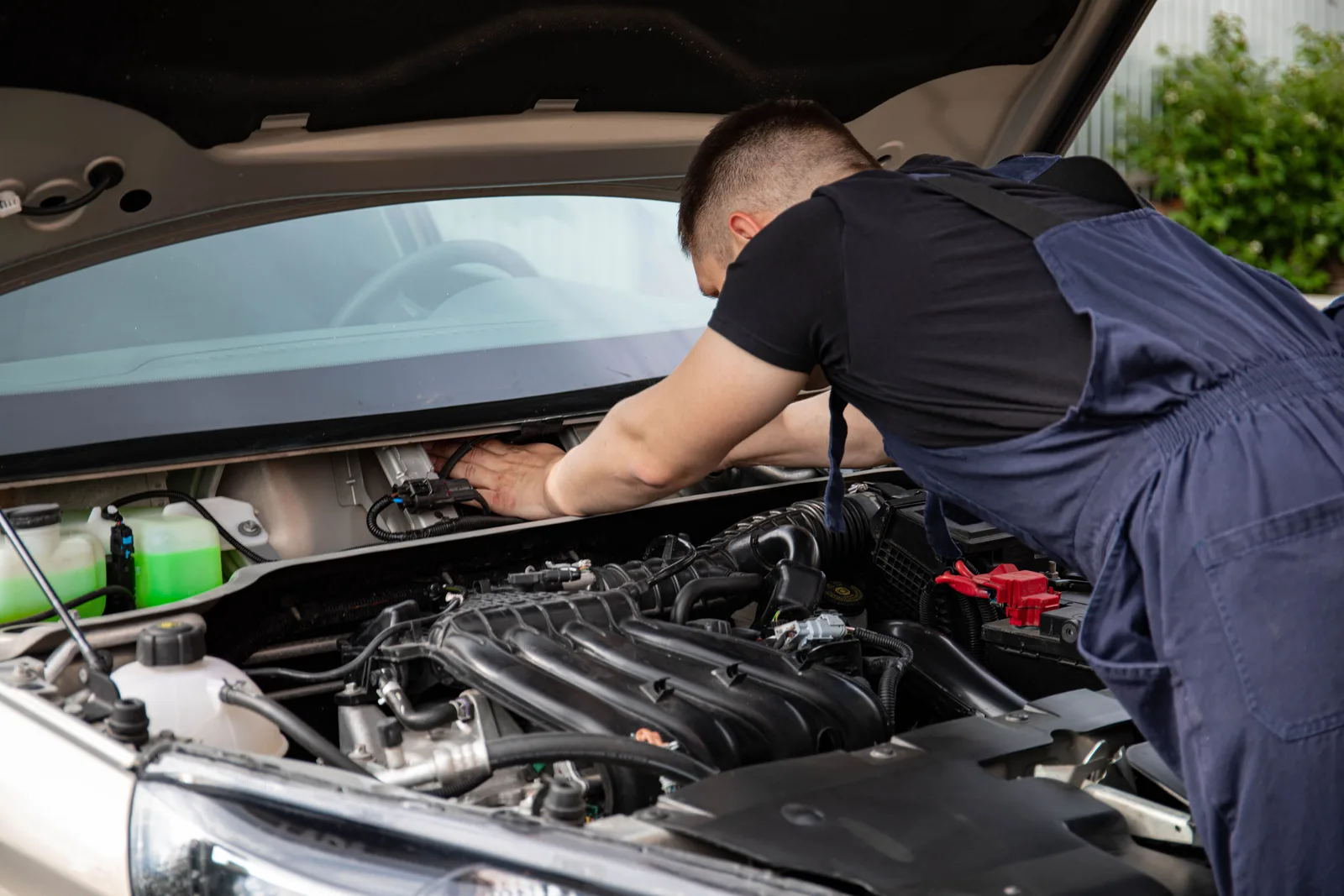 Mechanic working on a car engine with the hood raised