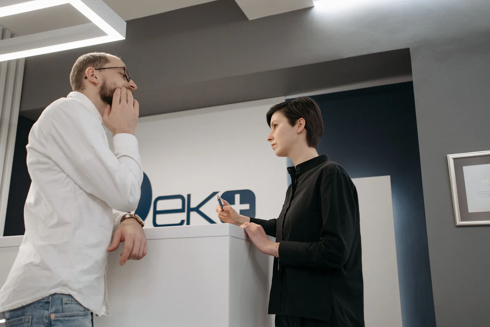 Bank staff member talking with a customer who is leaning on a reception counter
