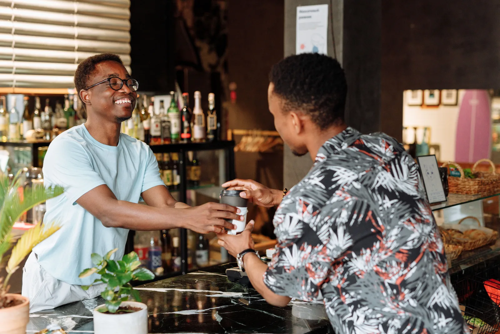 A member of staff handing a takeaway cup across a cafe counter to a customer
