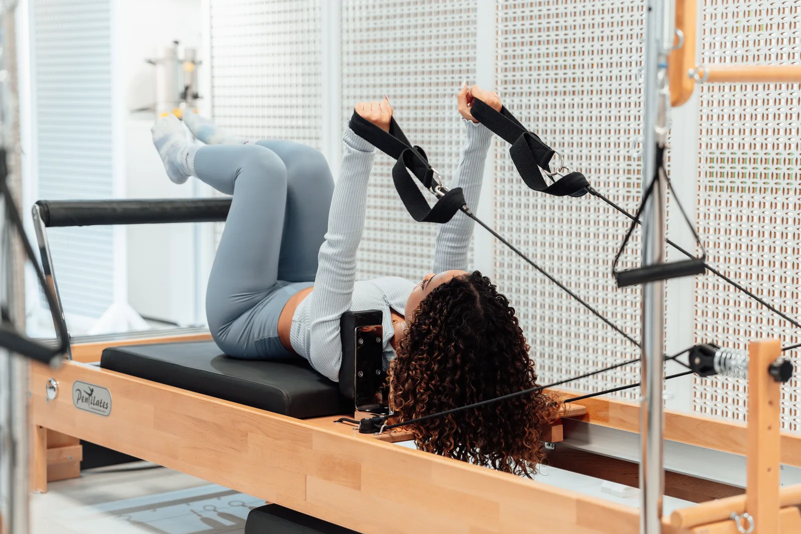 Una mujer haciendo ejercicio en un reformer de pilates en un estudio