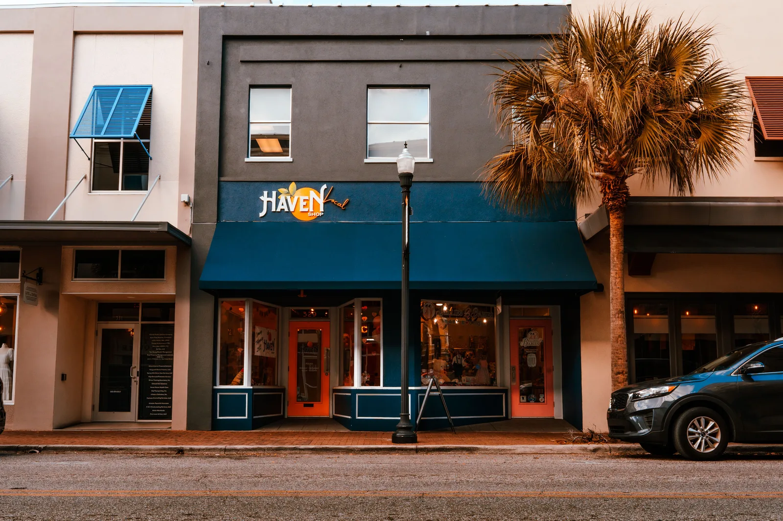 Independent boutique storefront with an awning and a palm tree on the pavement outside