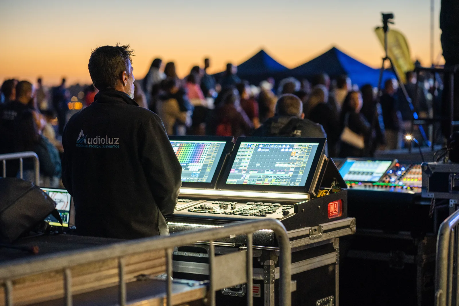A technician managing sound and lighting panels during an outdoor event at sunset