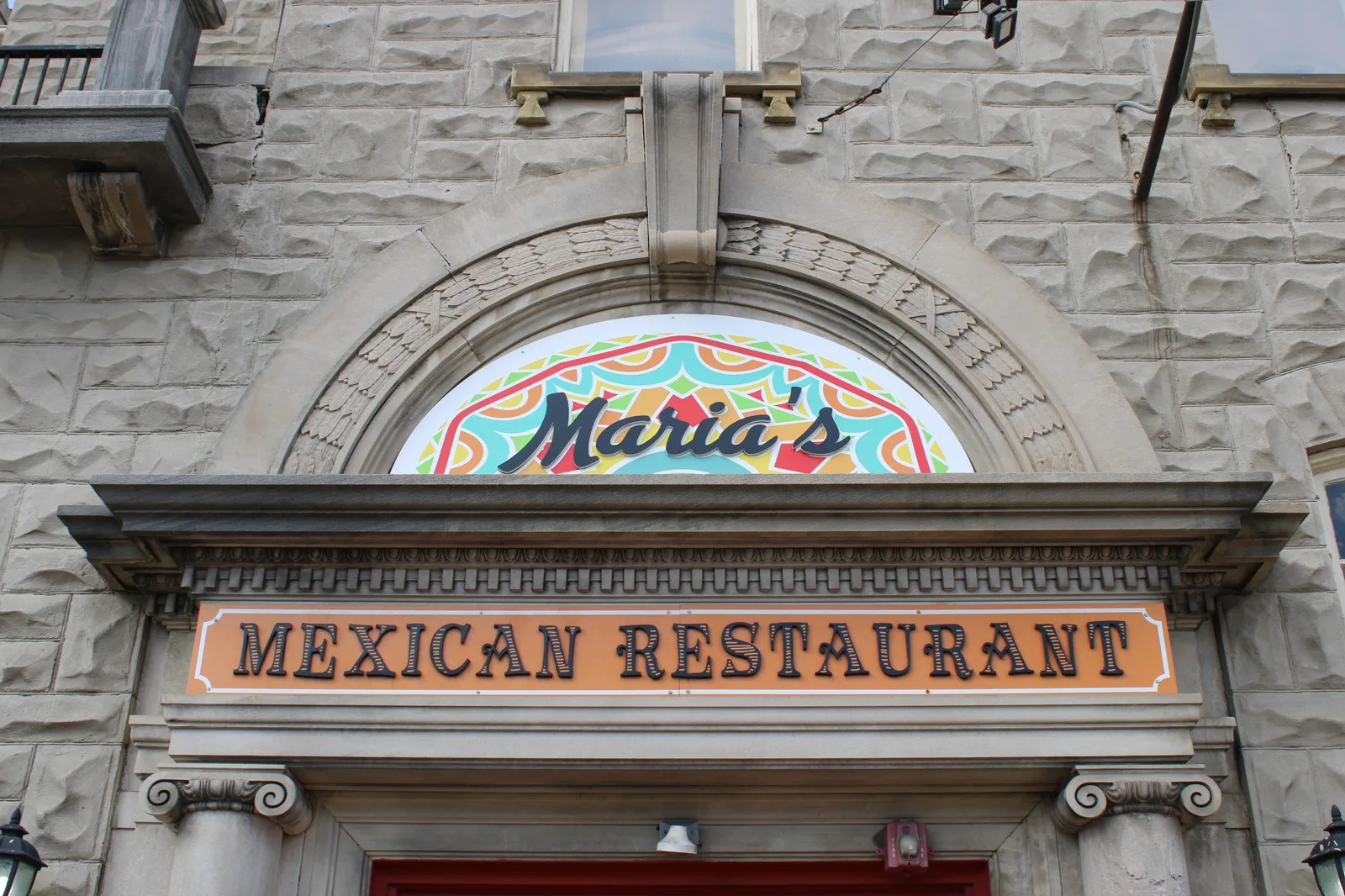 The arched stone facade and painted window signage of an independent Mexican restaurant in Lancaster, Ohio