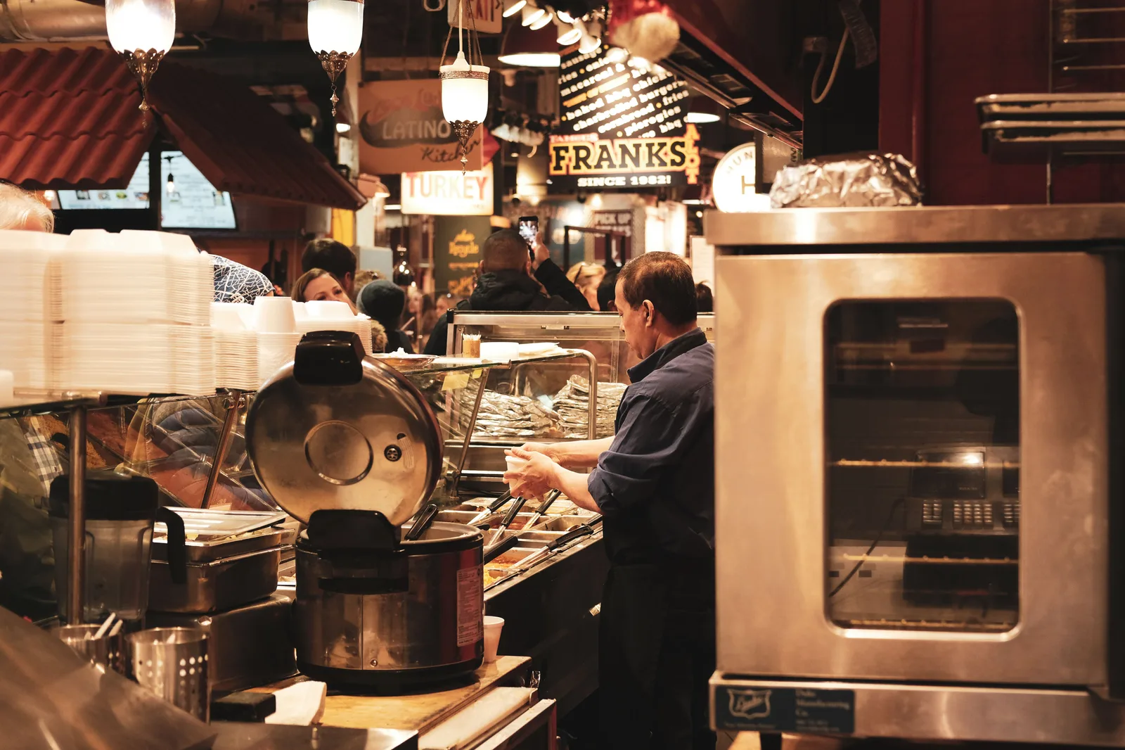 A busy food hall with a vendor preparing food