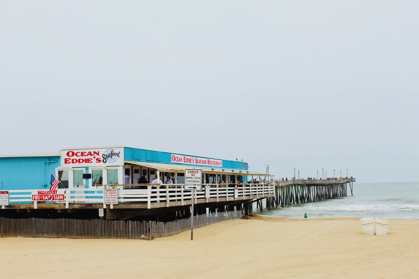 A seafood restaurant built on the Virginia Beach fishing pier, with diners under the awning and the pier running out over the water