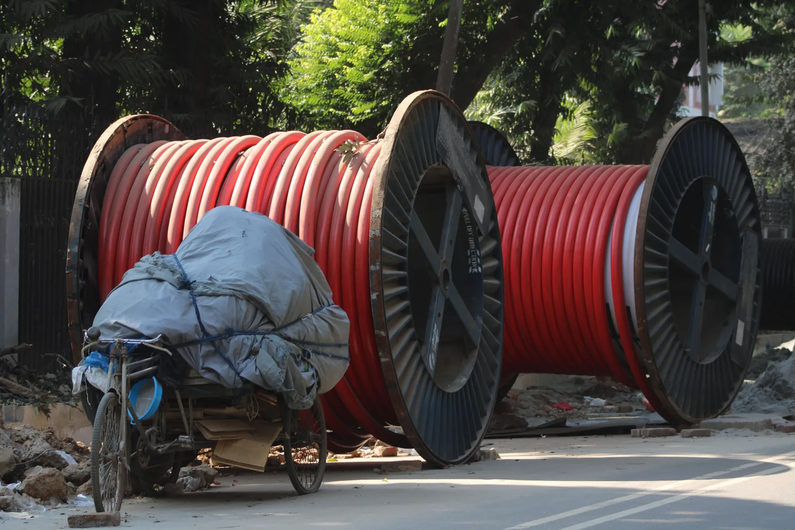 Two large reels of heavy red electrical cable standing on a construction site