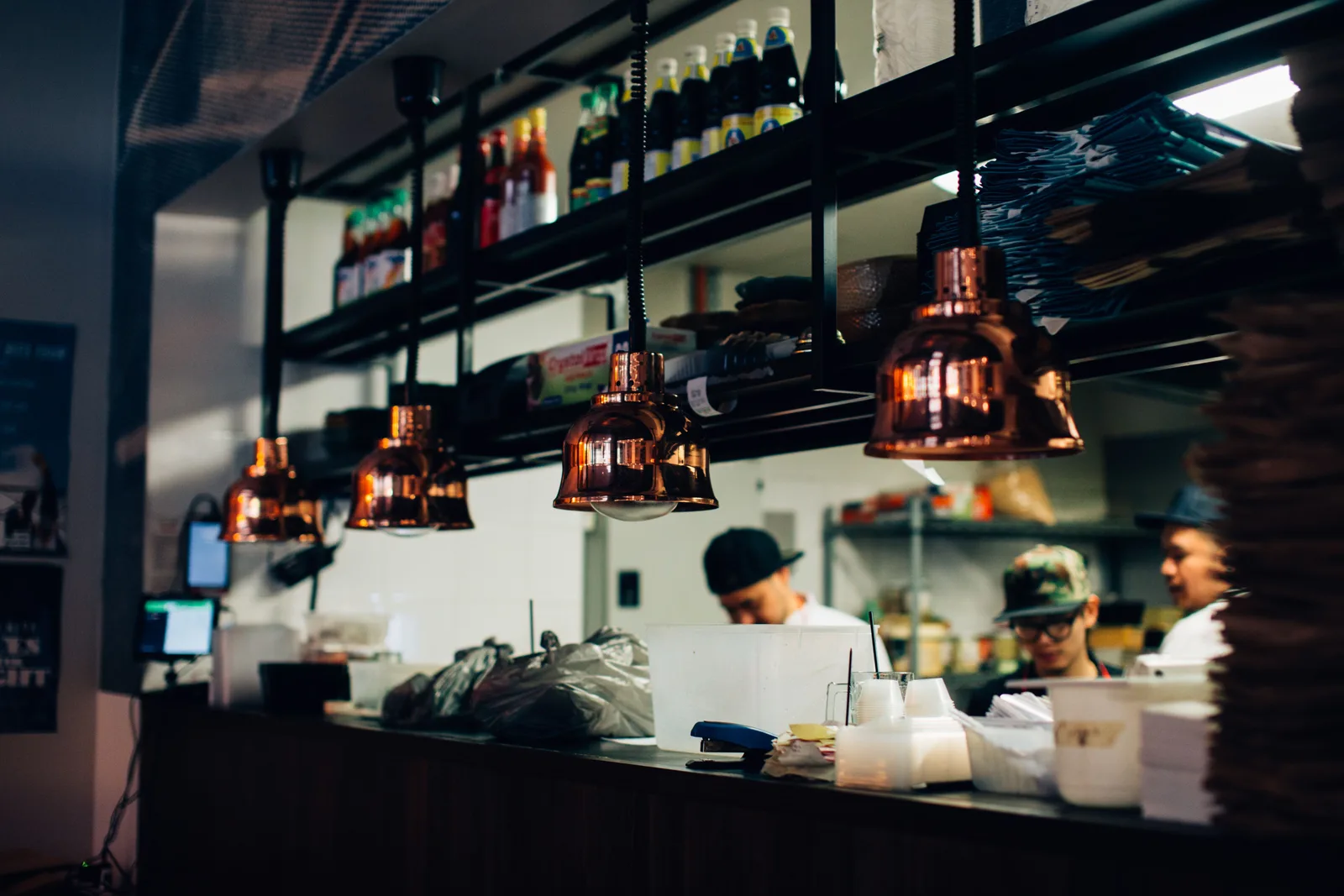 Kitchen staff working behind a service pass under heat lamps in a restaurant