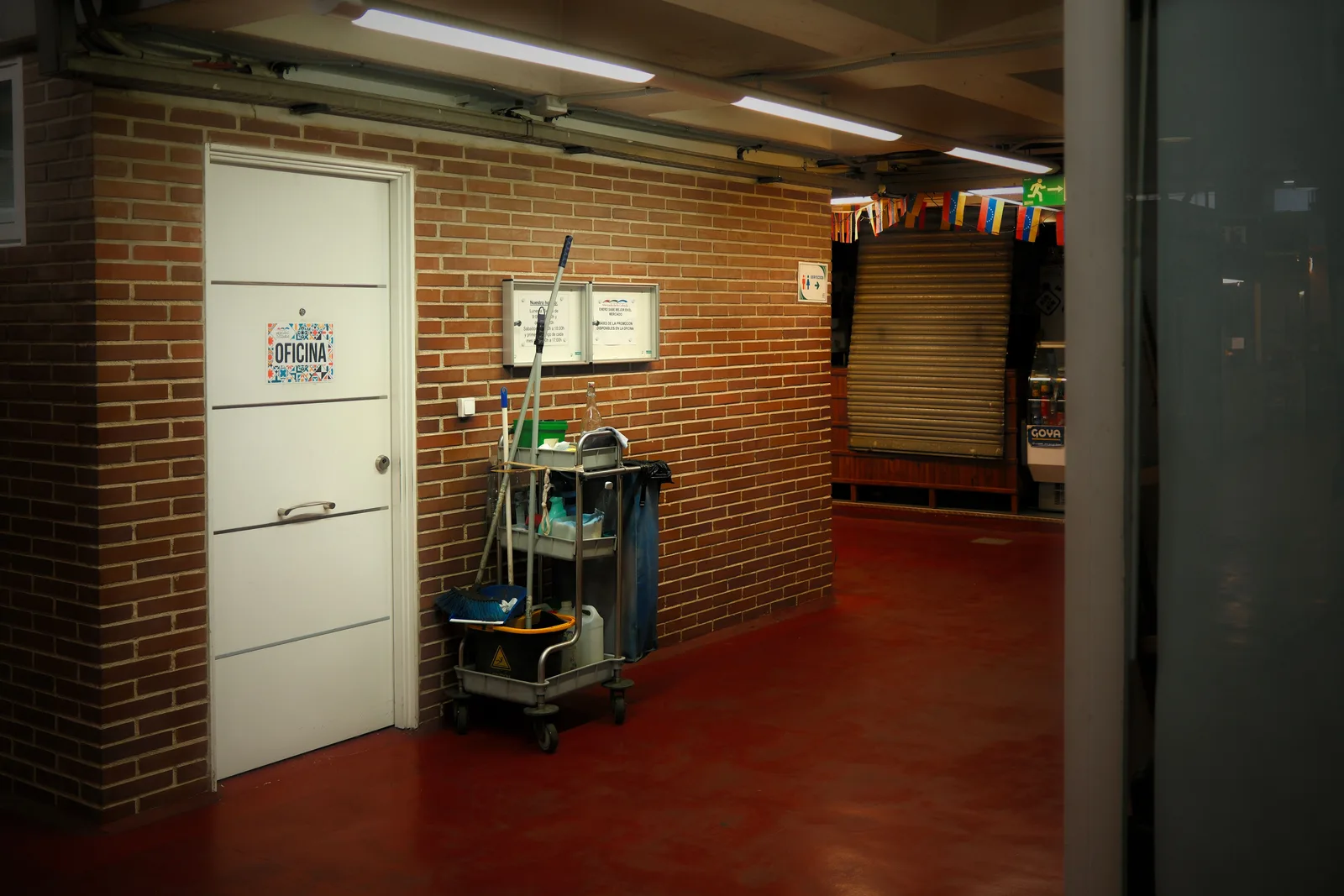 A stocked janitorial supply cart parked in a lit office corridor beside a closed office door