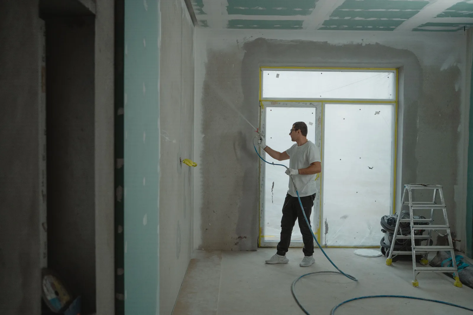 Contractor using a paint sprayer on an interior wall