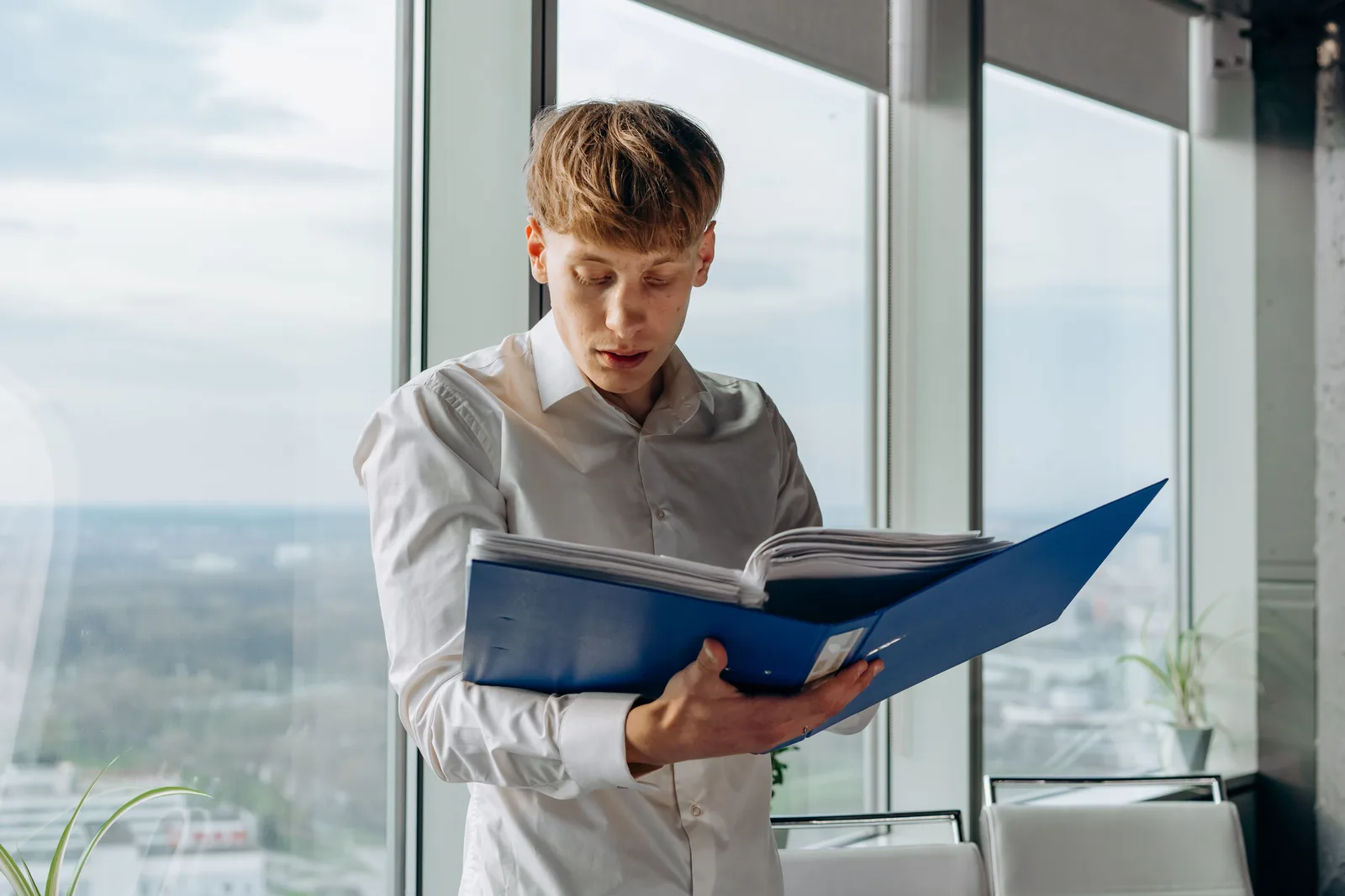Person in an office reading documents from an open ring binder