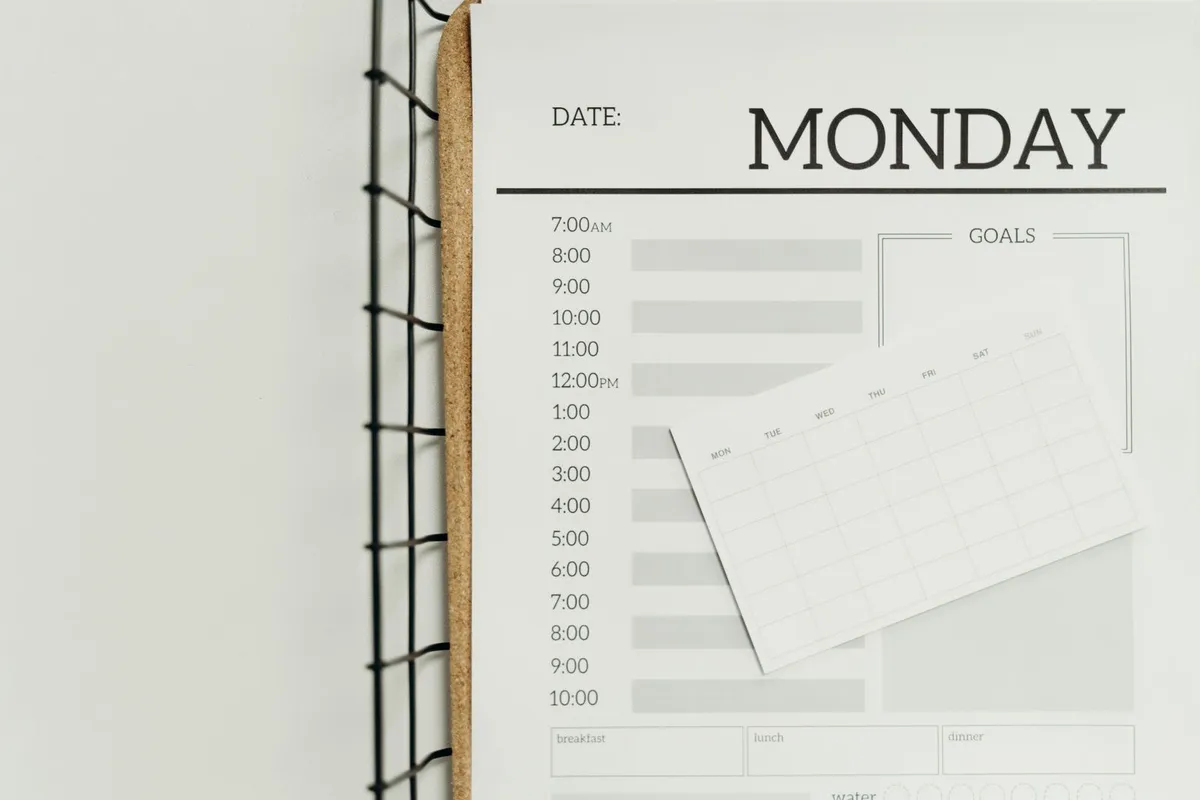 A weekly planner page headed Monday with a small week-at-a-glance calendar card laid on top of it
