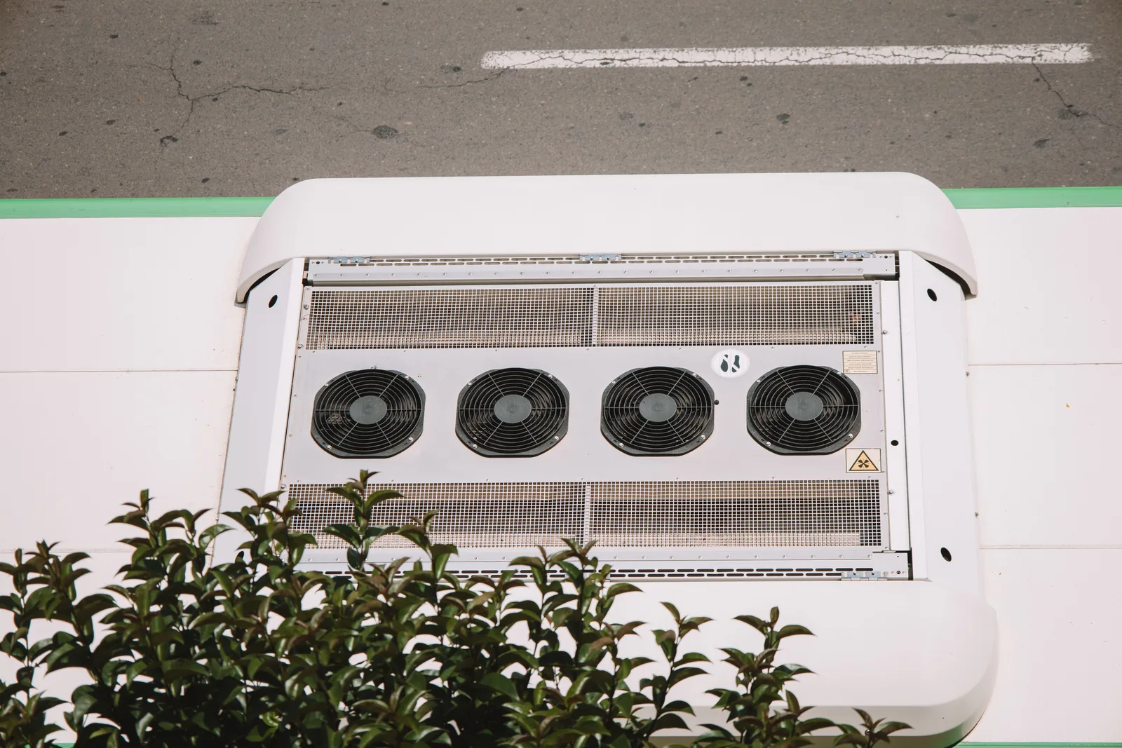 Overhead view of a rooftop air conditioning unit with large fans on a commercial building