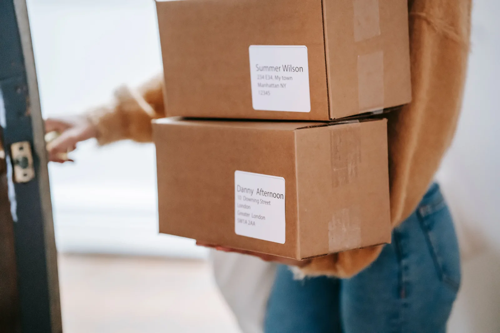 Seller carrying two address labeled parcels out through a doorway