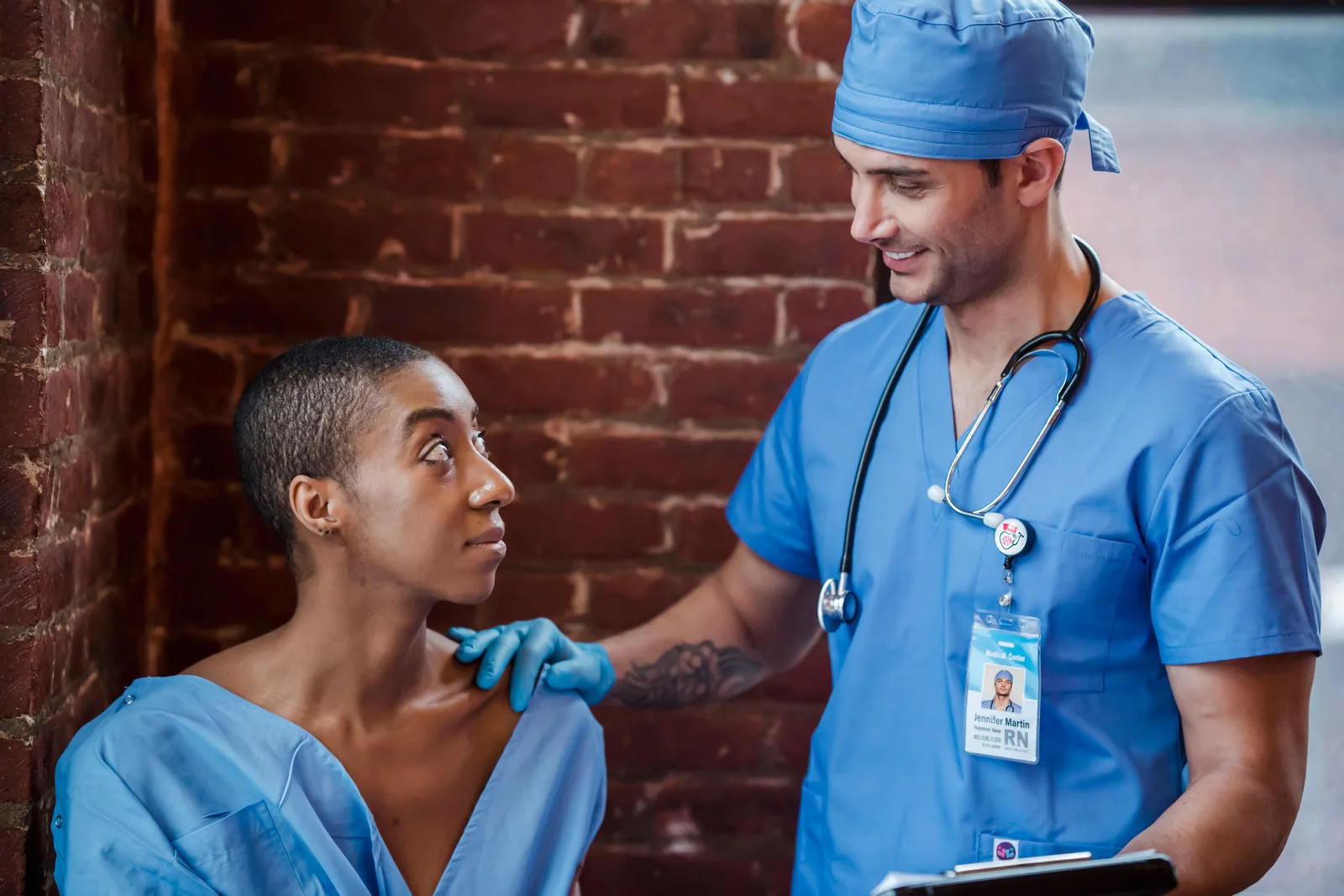 A clinician in scrubs holding a clipboard while examining a patient's neck