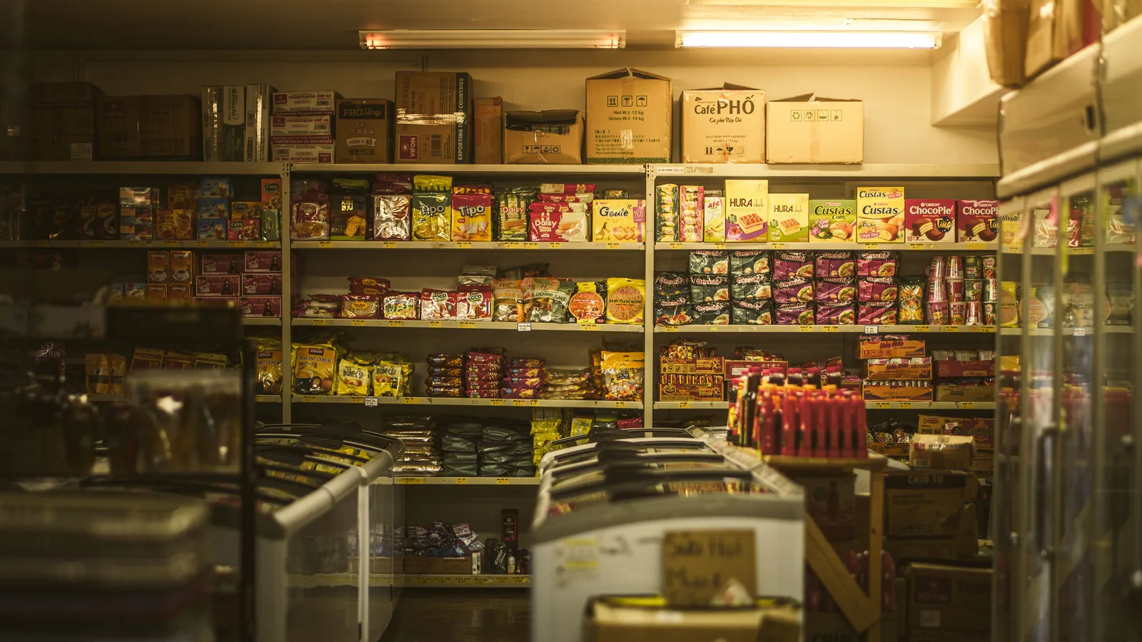 Packed shelves of packaged food and drinks in a small independent grocery store