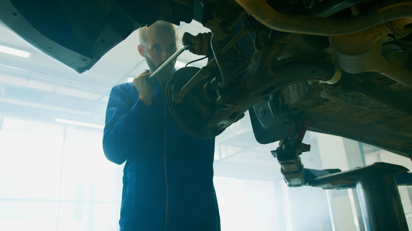 A mechanic working underneath a vehicle raised on a lift
