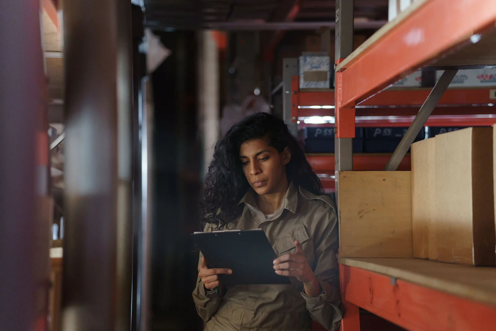 A worker checking stock against a clipboard in a storeroom
