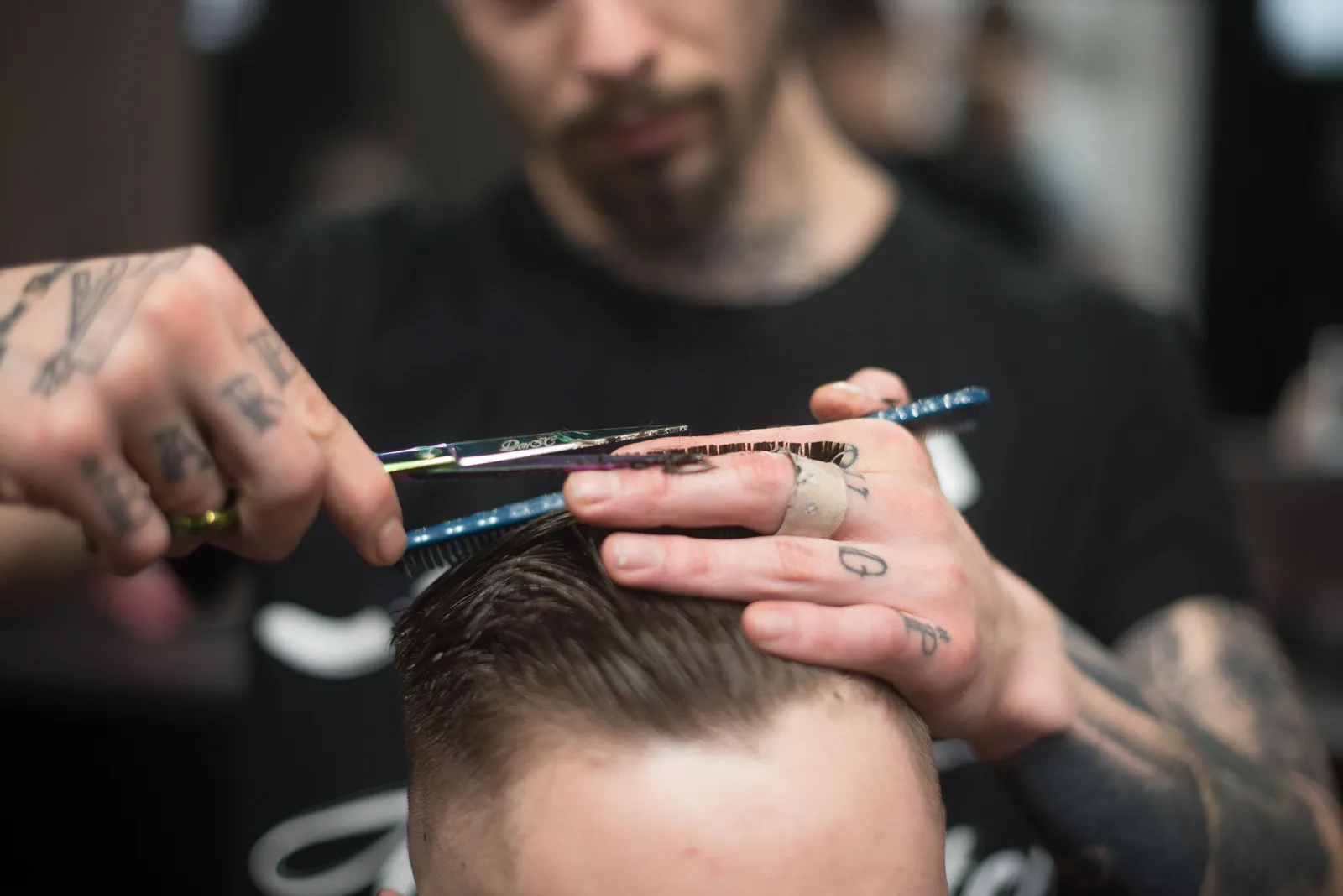 A barber cutting a client hair with scissors and a comb