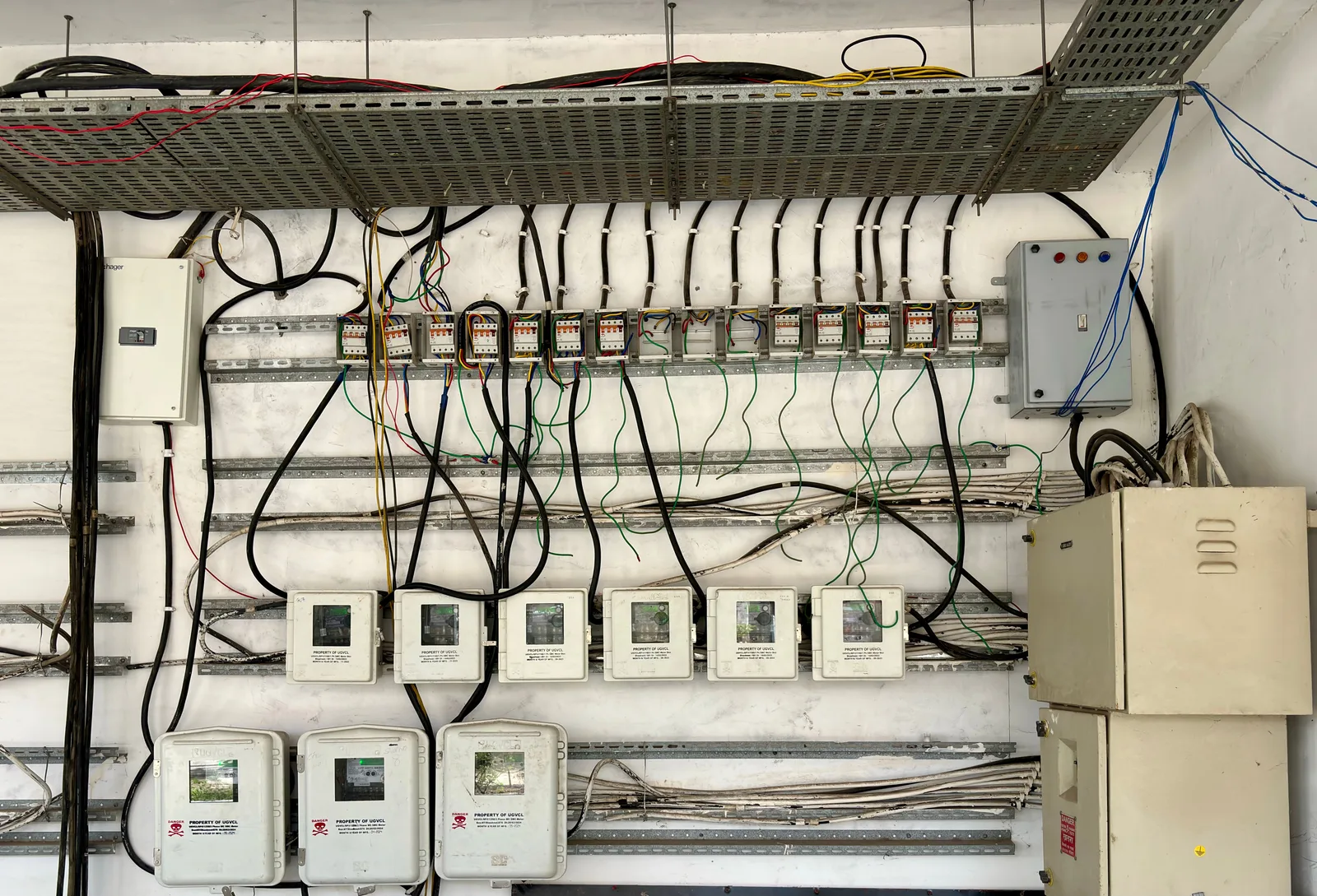 A wall of electrical distribution panels, meters and wiring inside an industrial building