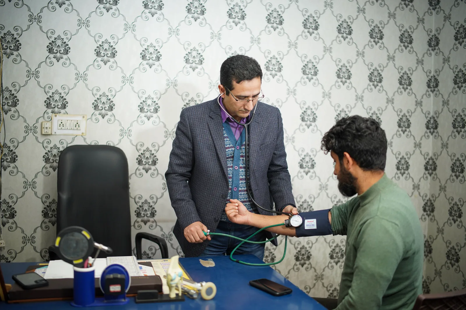 A doctor taking a seated patient's blood pressure with an arm cuff