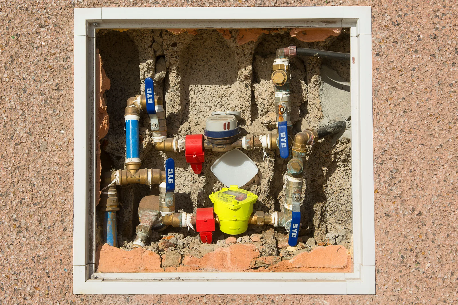 A water meter and valve assembly mounted inside a recess in a building wall