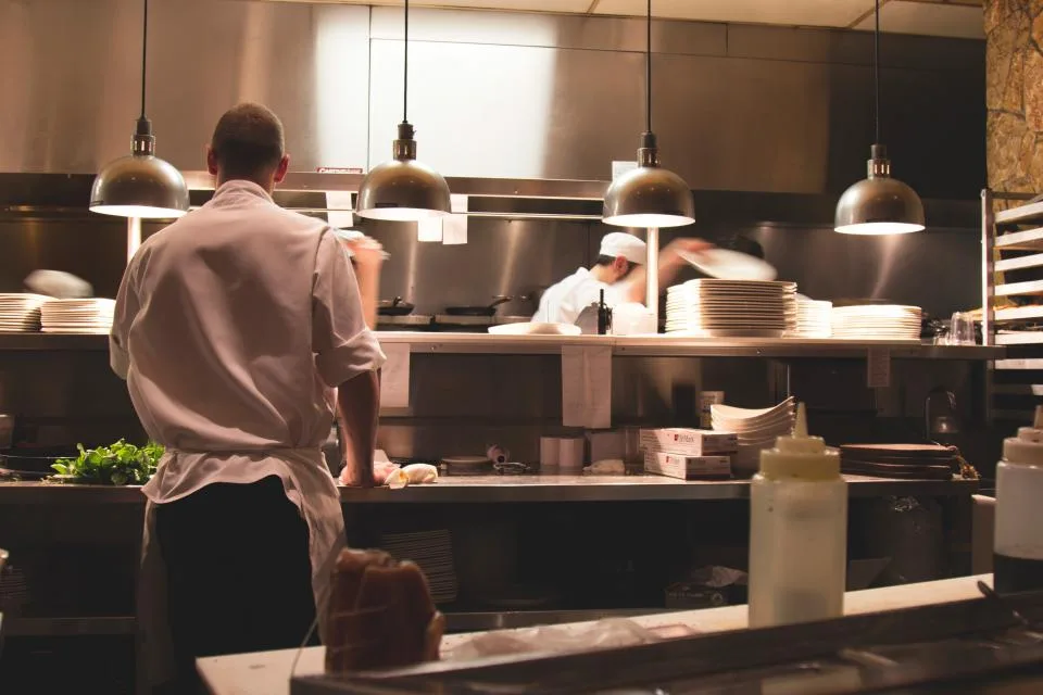 Wide view of a busy commercial restaurant kitchen during service