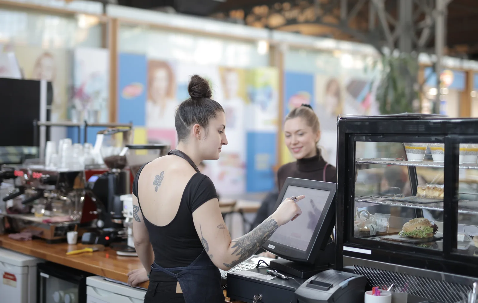 A cafe worker ringing up a customer order on a touchscreen till at the counter