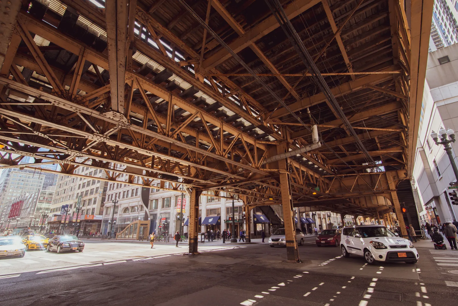 Traffic and storefronts on a downtown Chicago street beneath the elevated train structure