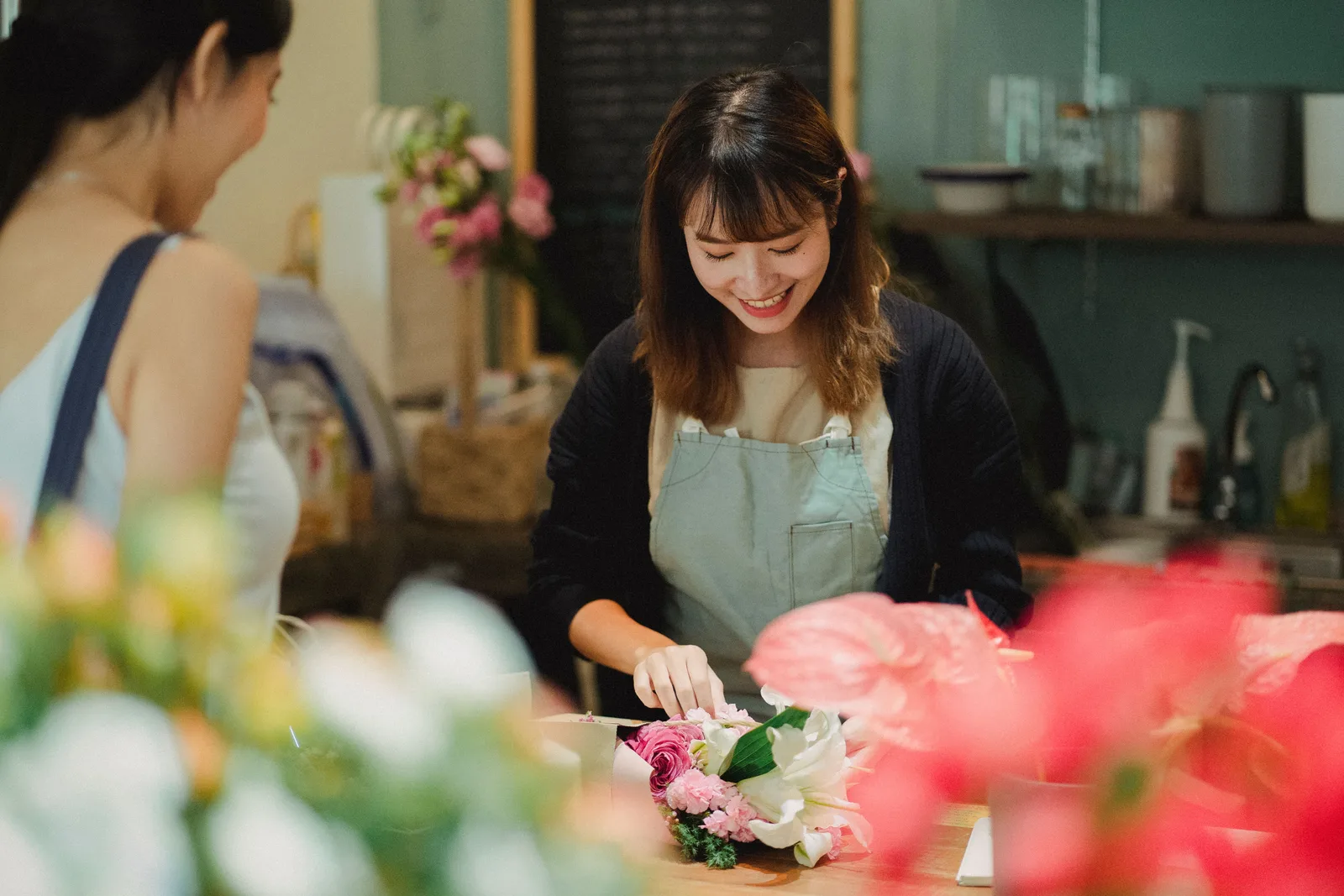 A florist arranging a bouquet for a customer at the shop counter