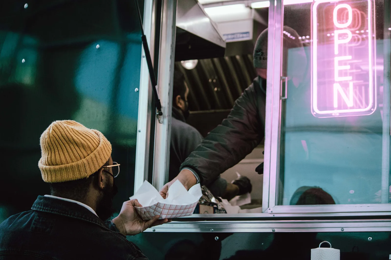 A customer taking an order at the service window of a street food truck at night
