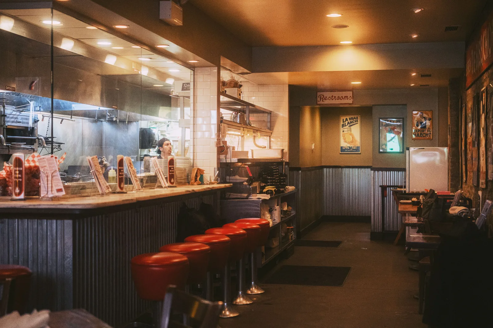 The interior of a diner with counter stools and an open kitchen