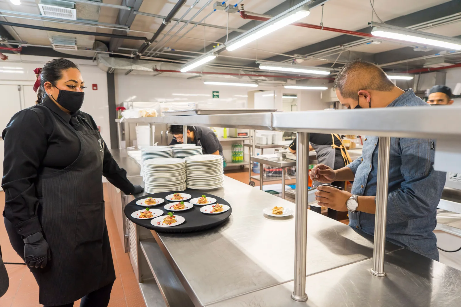 Chefs plating dishes on the pass in a commercial kitchen