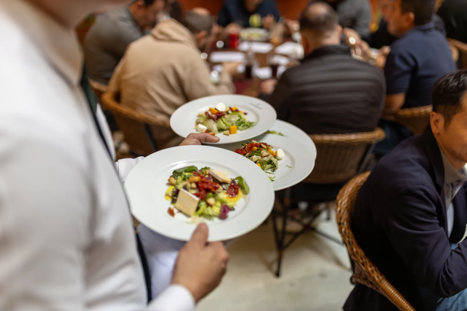 A waiter serving plates to a table in a busy restaurant