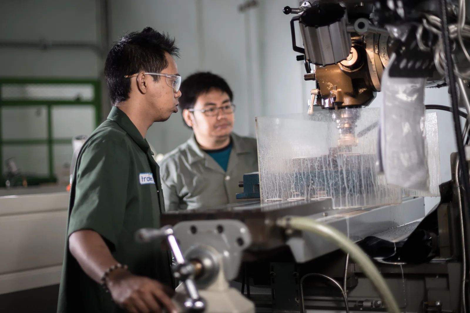 Two technicians operating a milling machine in a workshop