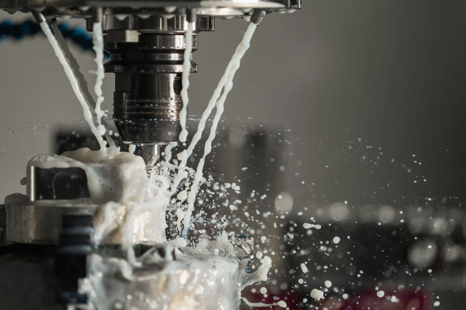 Coolant sprays from the spindle of a CNC machine as it cuts into a metal part.