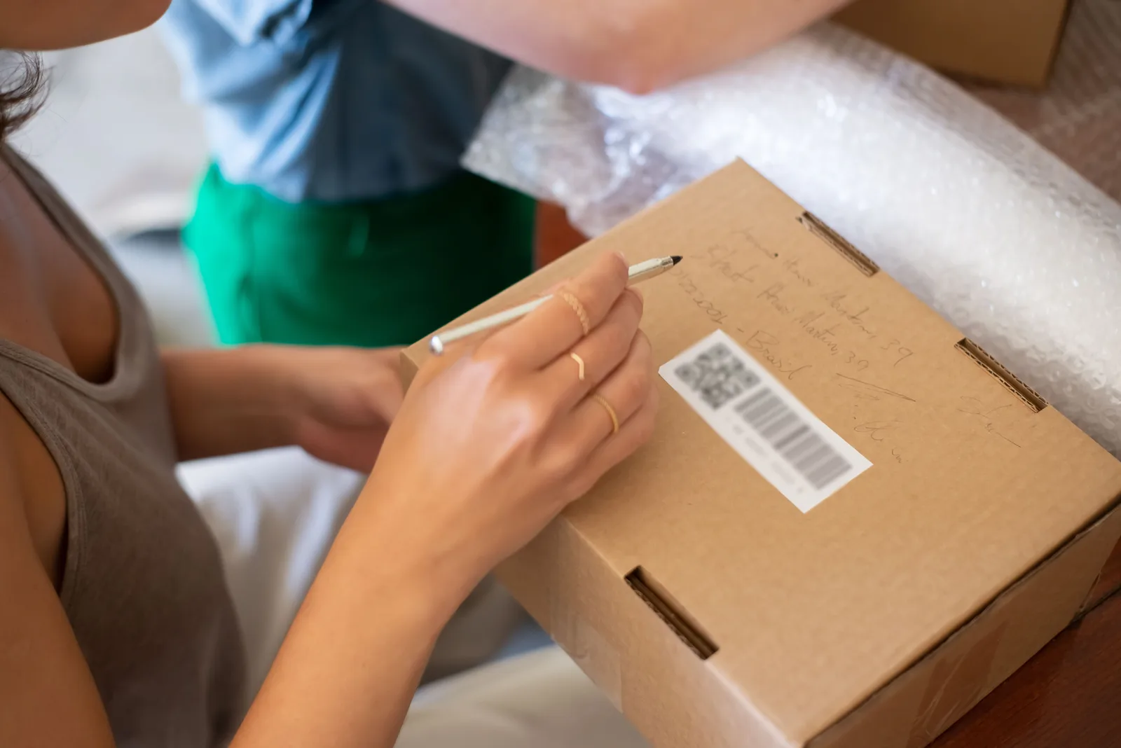 Person writing shipping details on a labeled cardboard box