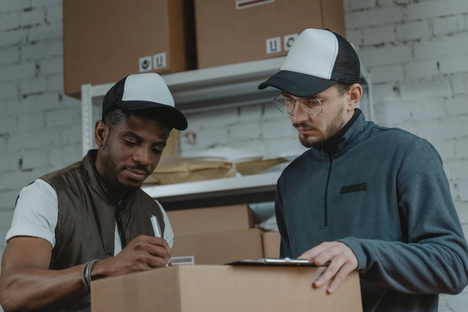 Two workers checking paperwork over a box in a parcel warehouse