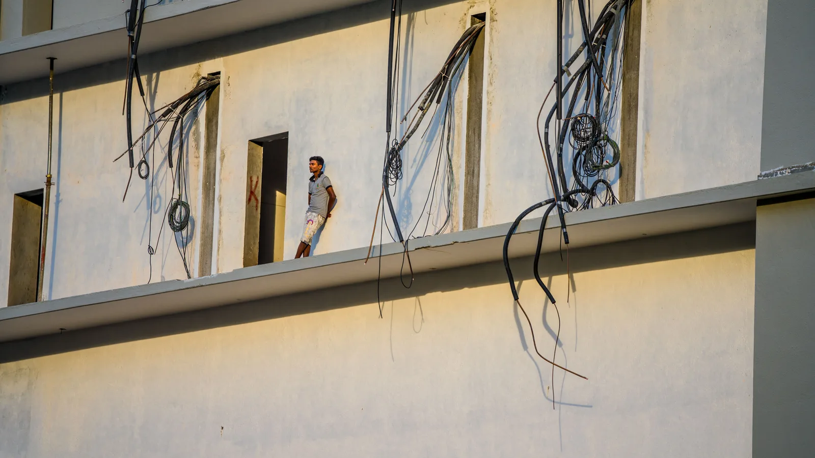 Electrical cable drops hanging from openings in an unfinished building at a construction site
