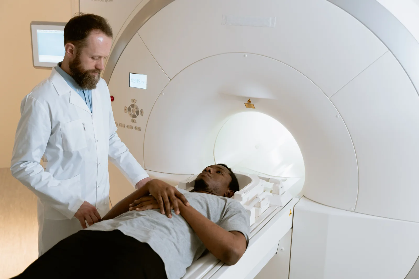 A radiographer preparing a patient at the opening of an MRI scanner