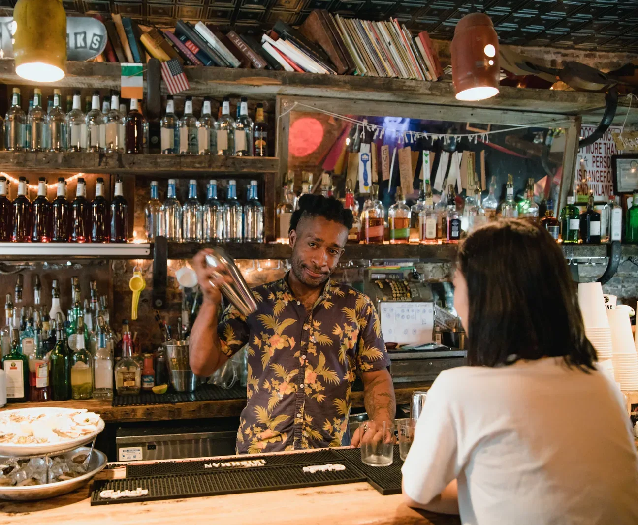 Bartender shaking a cocktail for a customer seated at a neighborhood bar