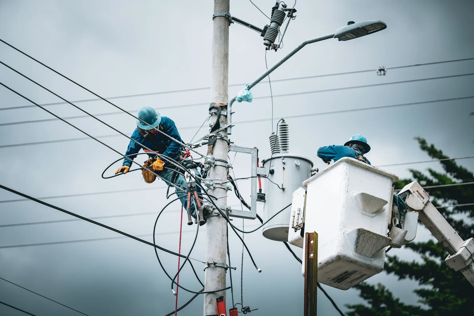 Electricistas trabajando desde una canastilla elevadora en líneas aéreas sobre una calle de la ciudad