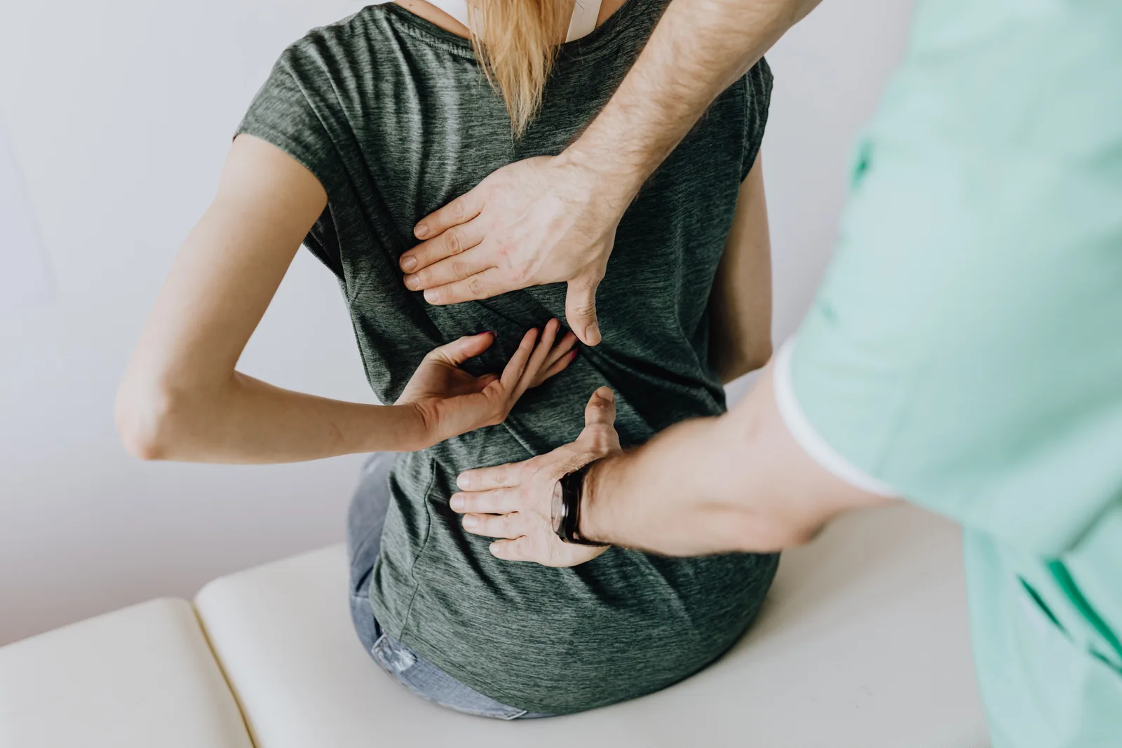 A clinician examining a seated patient's back during an appointment