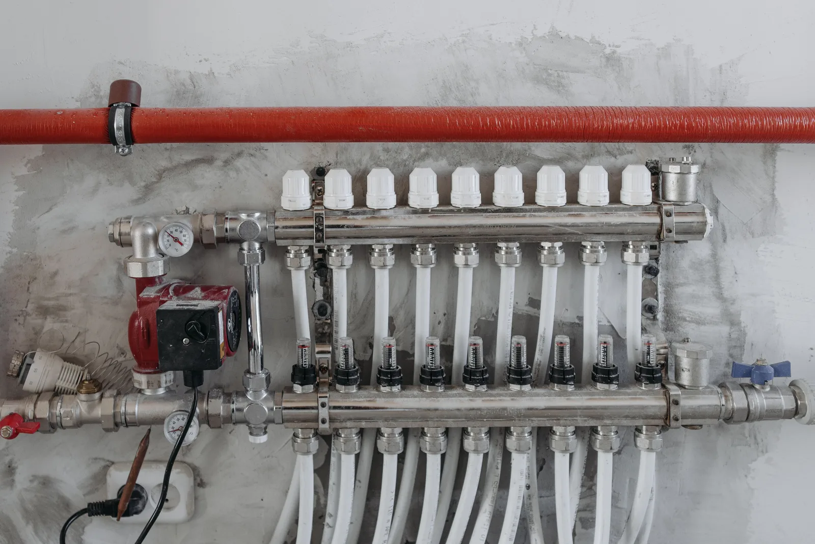 A building mechanical manifold with a circulator pump, pressure gauge and a row of flow meters