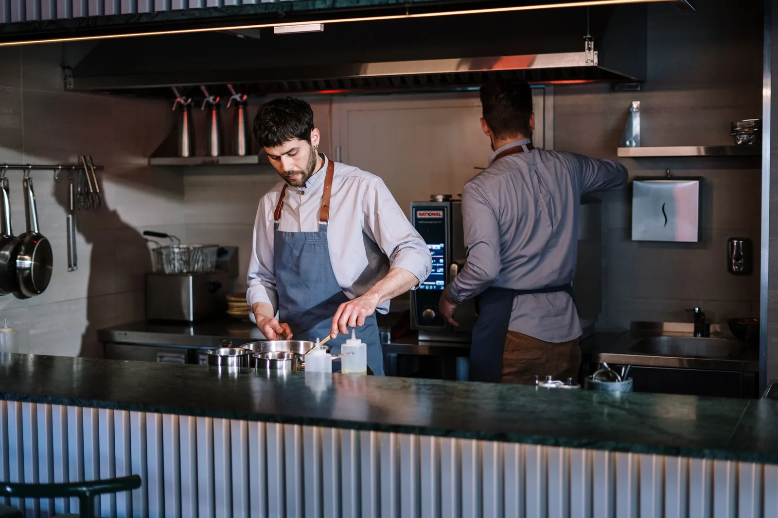 Two cooks working behind the counter of an open restaurant kitchen