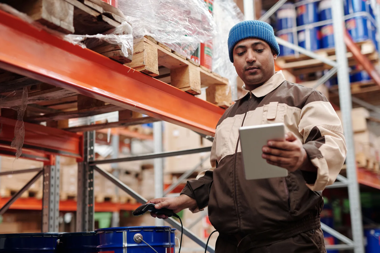 Warehouse employee scanning stock on a tablet in front of pallet racking