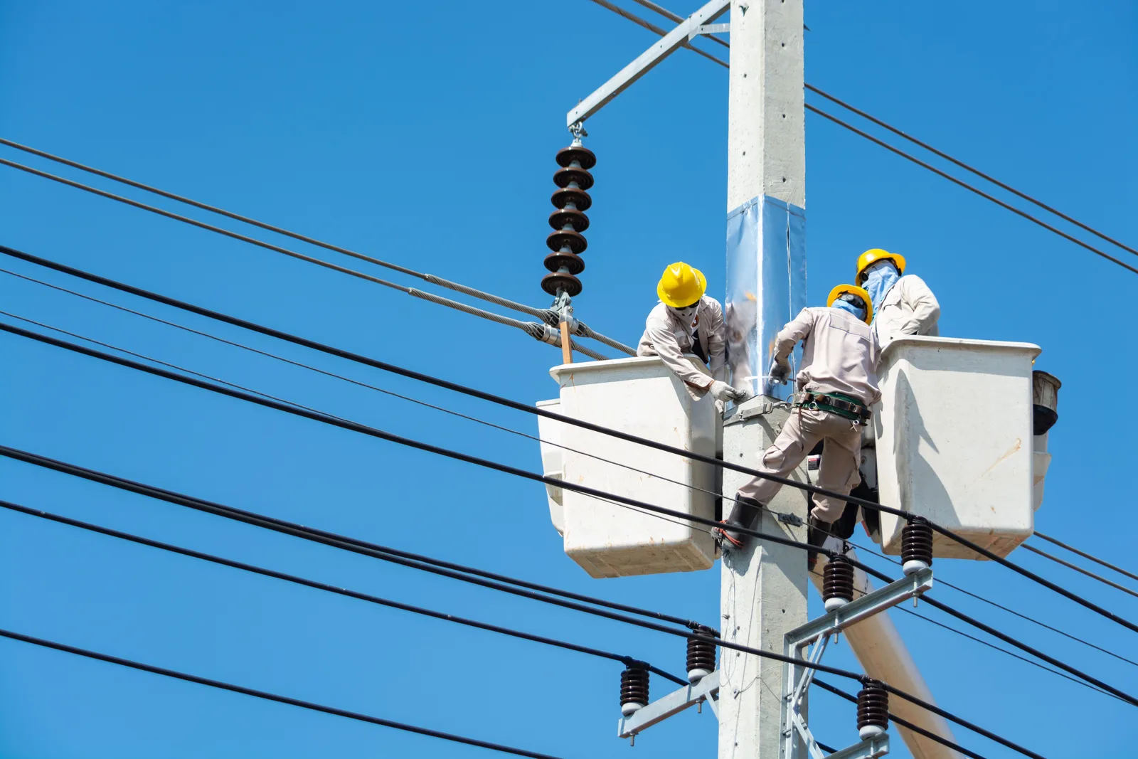 Two electricians in insulated lift buckets working on overhead power lines