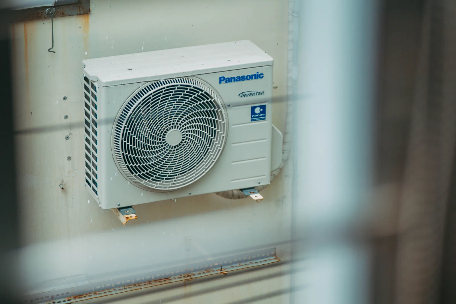 An outdoor air conditioning condenser unit mounted on the wall of a building