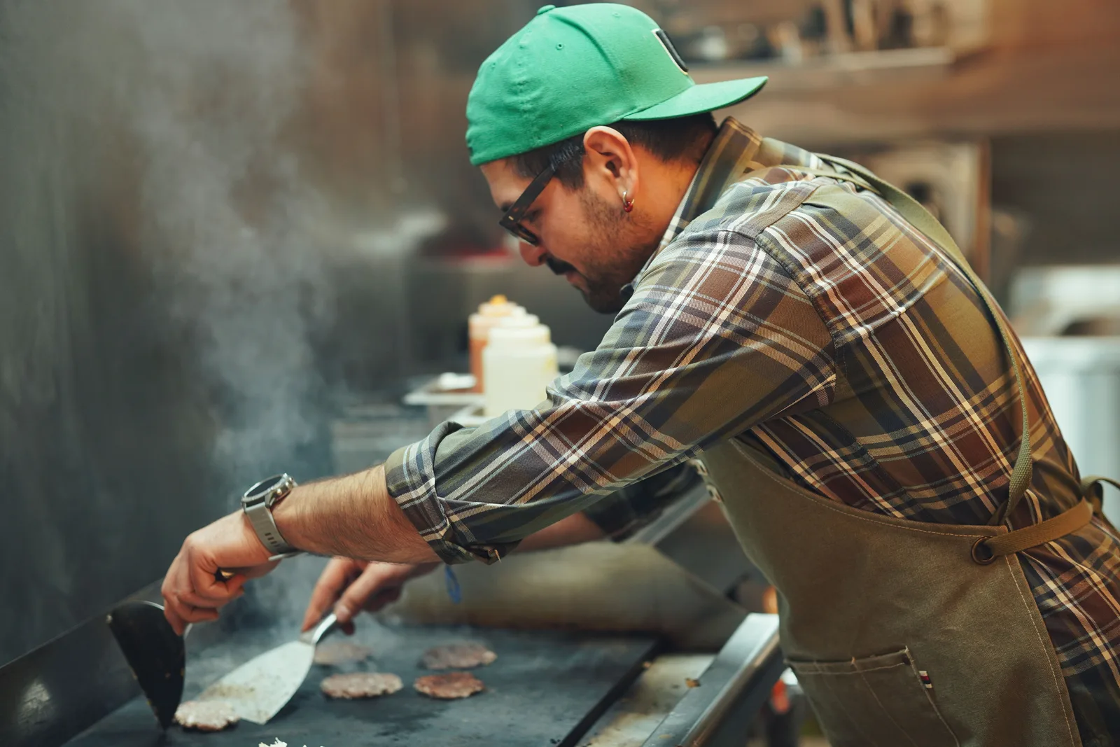 Cook working the grill station during an active kitchen service