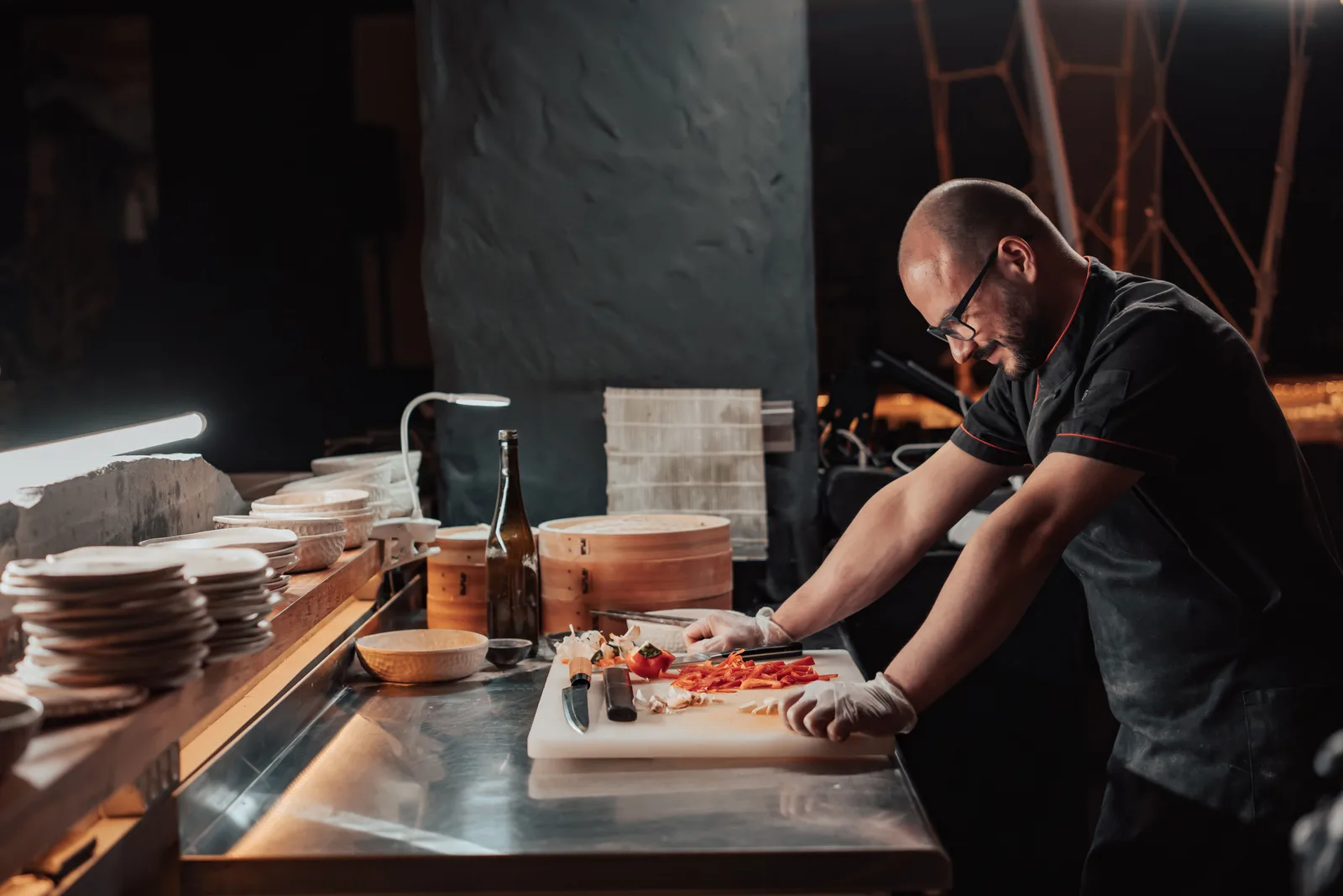 Line cook arranging prepped ingredients in stainless steel pans before service