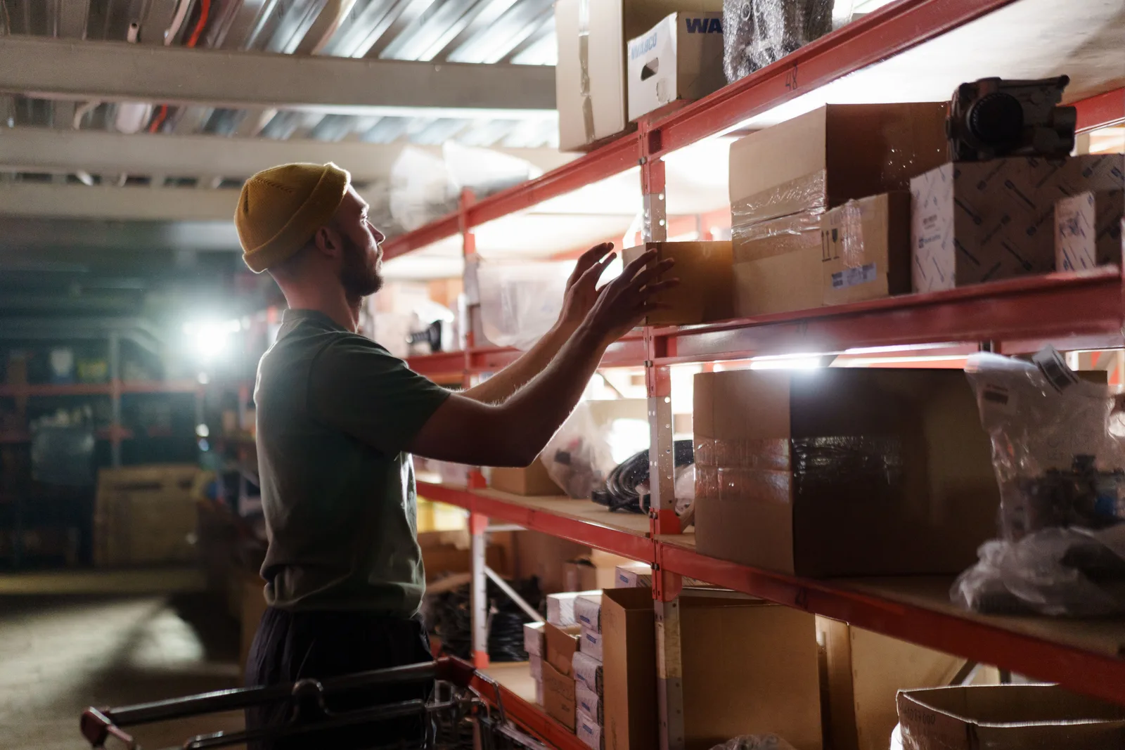 Worker lifting stock down from a warehouse shelf